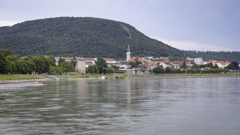 View of Hainburg/Danube on the river bank with a hill in the background.
