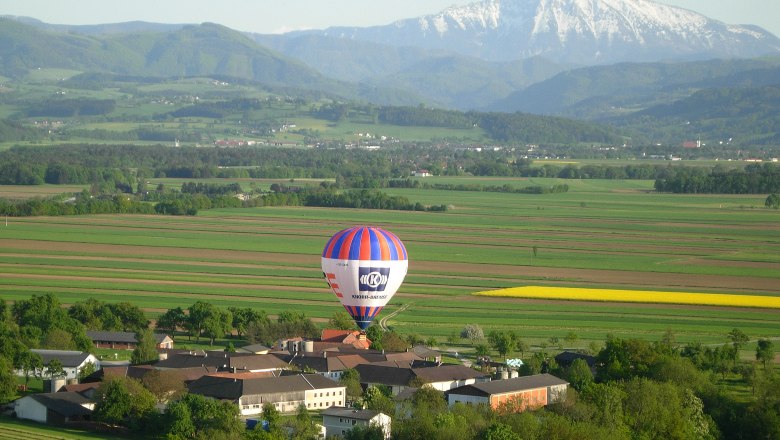 Hot air balloon over a rural landscape with mountains in the background.