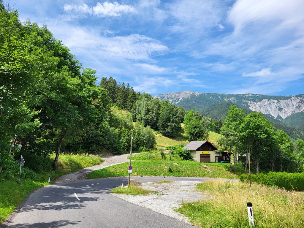 Landscape with road, house and mountains in the background.
