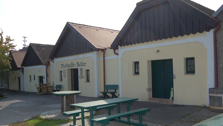 Traditional wine cellars with wooden benches and outdoor tables.