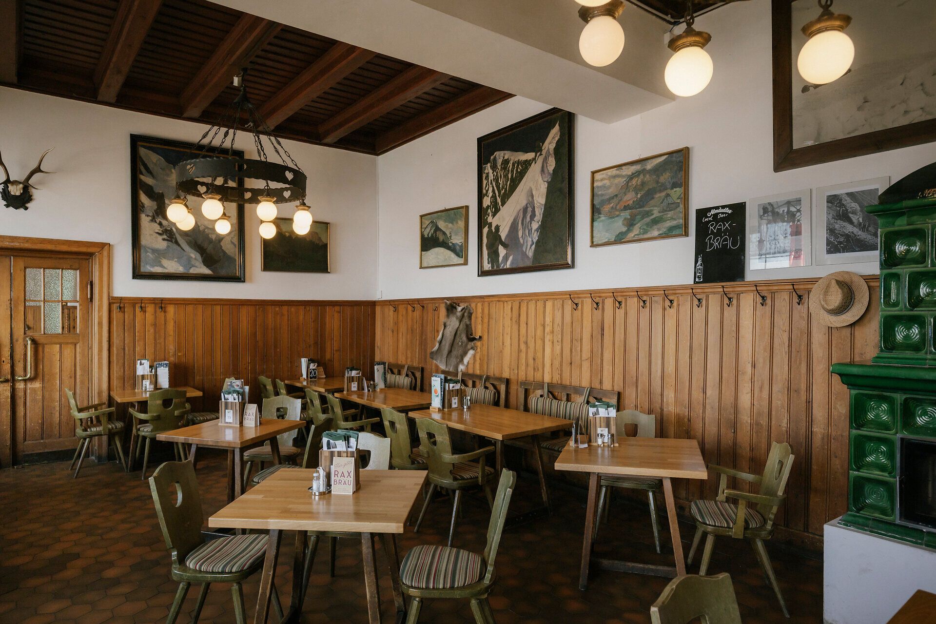 Dining room with a chandelier and Alpine paintings at the Raxalm Mountain Inn