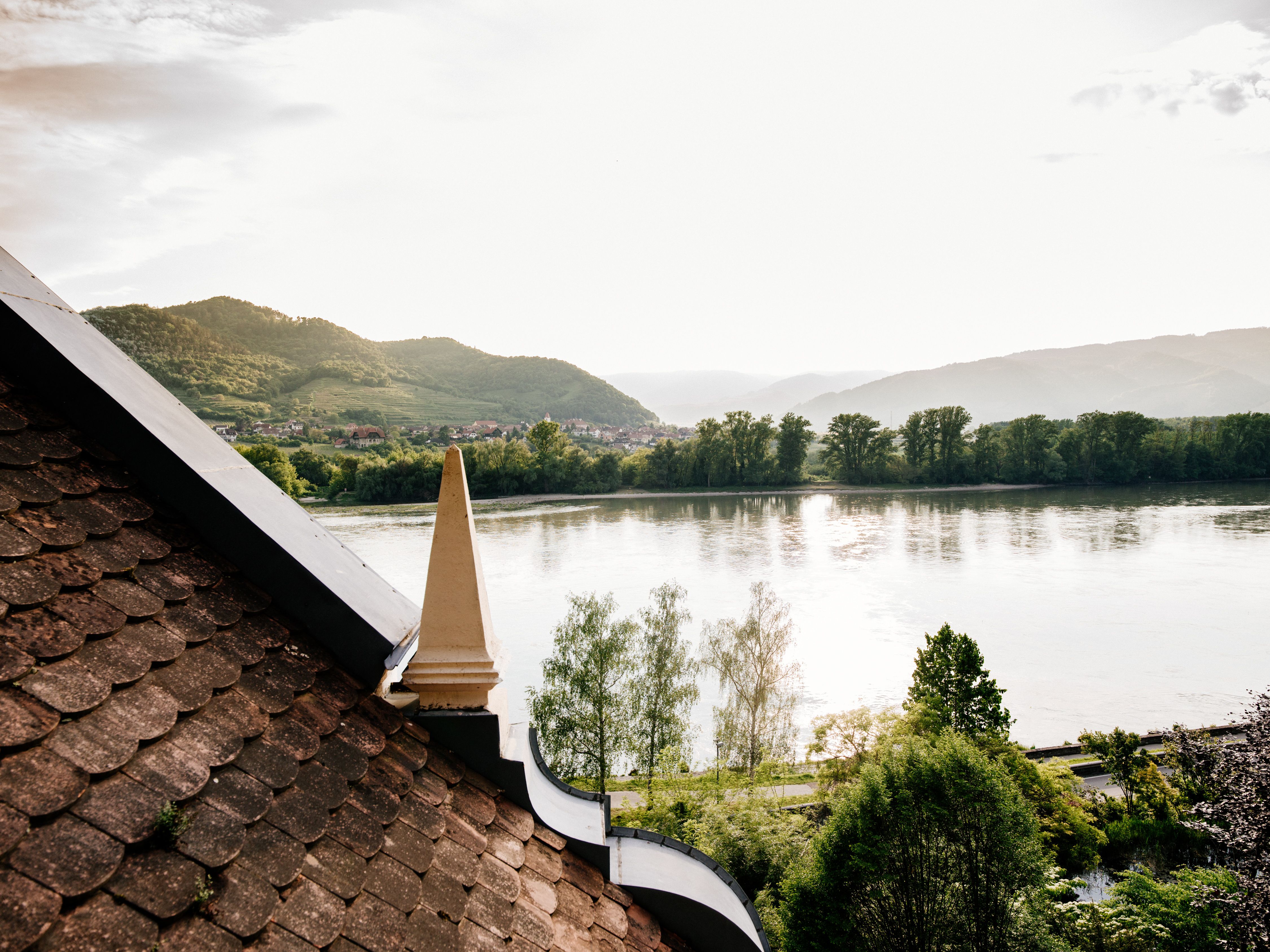 View from a roof onto a river and wooded hills in the background.