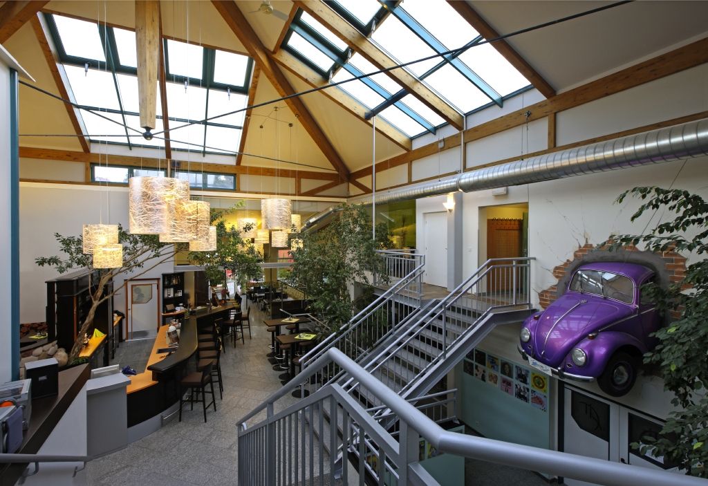 Interior view of a modern fitness center with glass roof, bar area and purple VW Beetle on the wall.