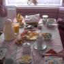 A laid breakfast table with bread rolls, cold cuts, cheese, juice and crockery.