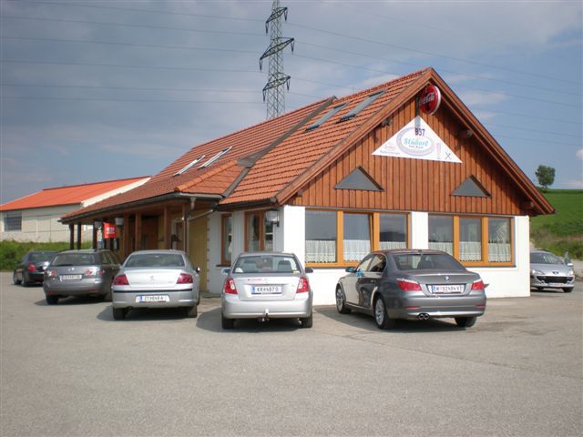 A restaurant with a wooden façade and several parked cars in front of it.