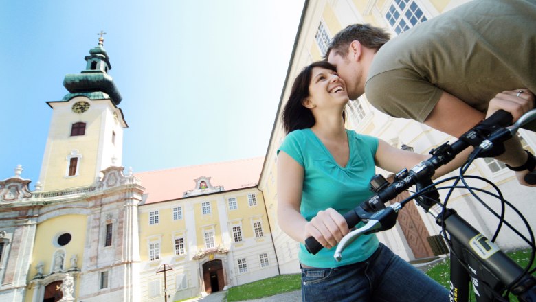 A couple with bicycles in front of Seitenstetten Abbey.