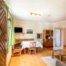 Dining room with wooden furniture, table with white tablecloth, green curtains and TV on the wall.