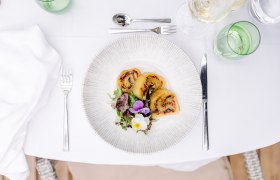 A plate of stuffed potato roulade and salad on a laid table.