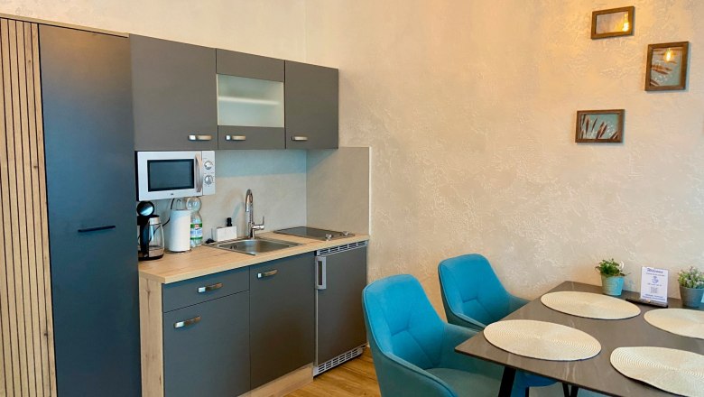 Modern kitchenette with gray cabinets and dining table with blue chairs.