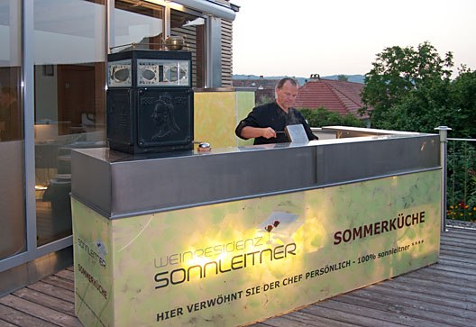 A chef prepares meals in an outdoor kitchen at the Sonnleitner wine residence.