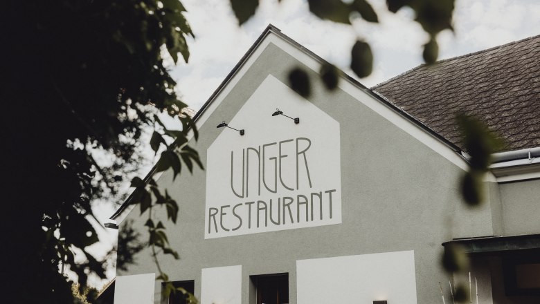 Exterior view of the Unger Restaurant with green building and lettering.