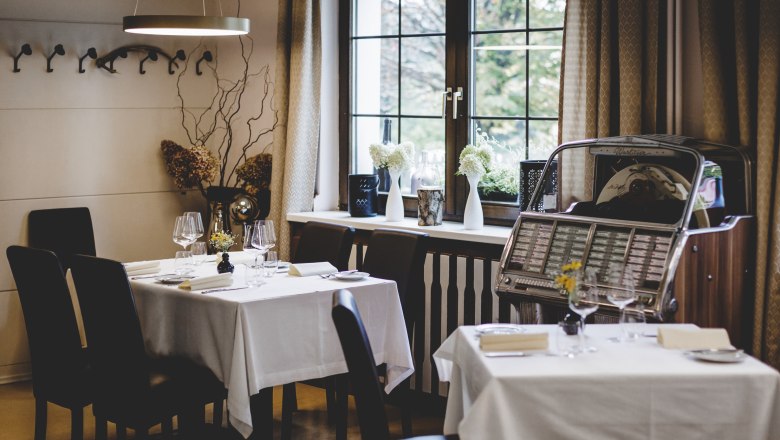 Cozy restaurant with set tables and jukebox by the window.