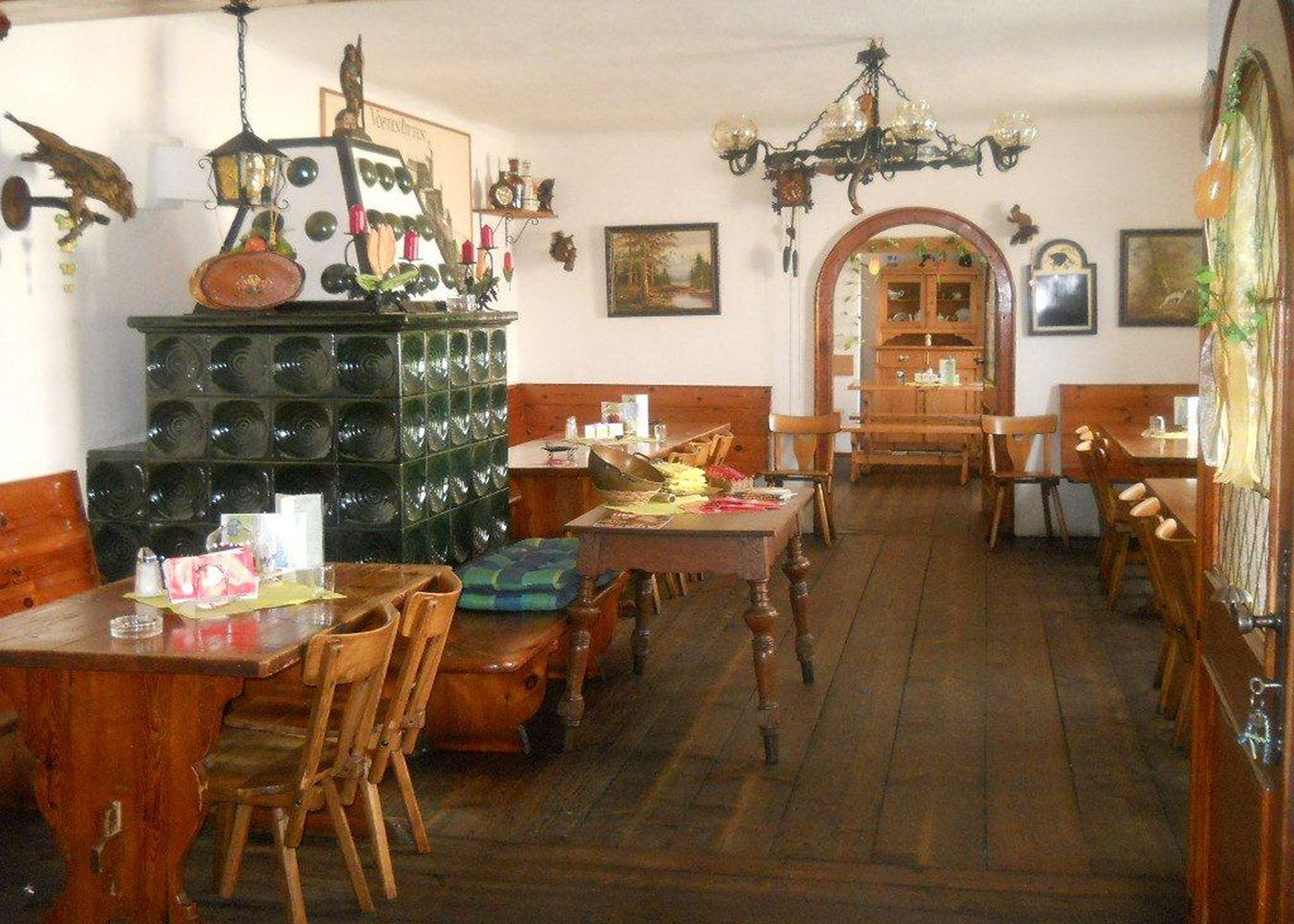 Interior view of a traditional Austrian wine tavern with wooden furniture and tiled stove.