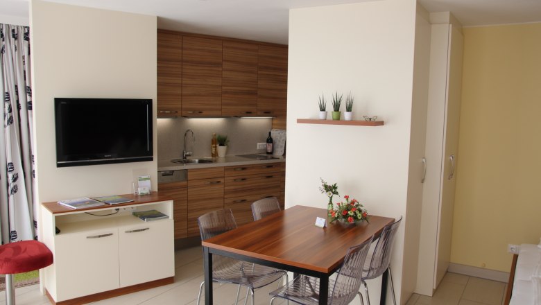 Modern garden apartment with kitchen, dining table and TV.