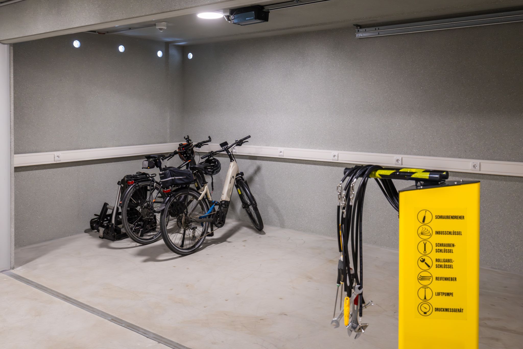 Bicycle storage room with two bicycles and a yellow tool station.