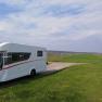 Motorhome on a pitch next to a vineyard under a blue sky.