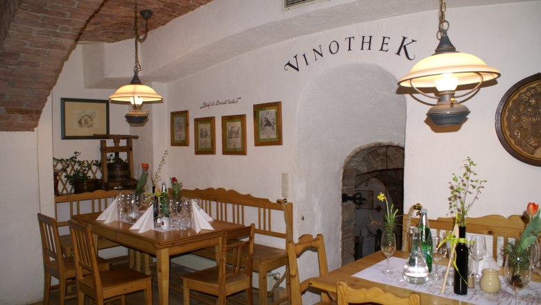 Interior view of a cozy wine bar with wooden furniture and decorated tables.