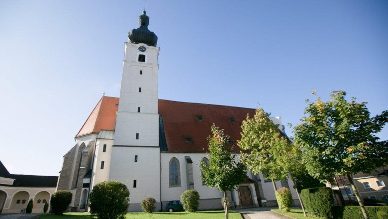 Mank pilgrimage church with tower and red roof, surrounded by trees and lawn.
