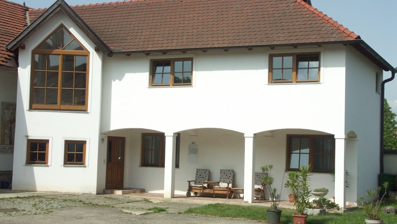 Wagner Winery, © Fam. Wagner A two-storey white building with red roof tiles and large windows. There are plants in pots in front of the house.