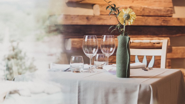 Elegant restaurant table with glasses and flower in vase.