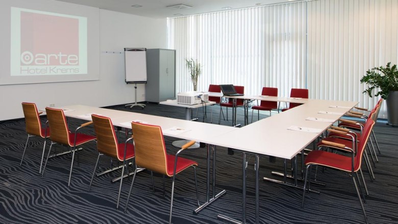 Conference room at the arte Hotel Krems with tables, chairs and presentation equipment.
