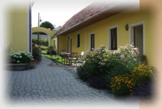 House view, © Der Teichhof Yellow house with garden and paved path.