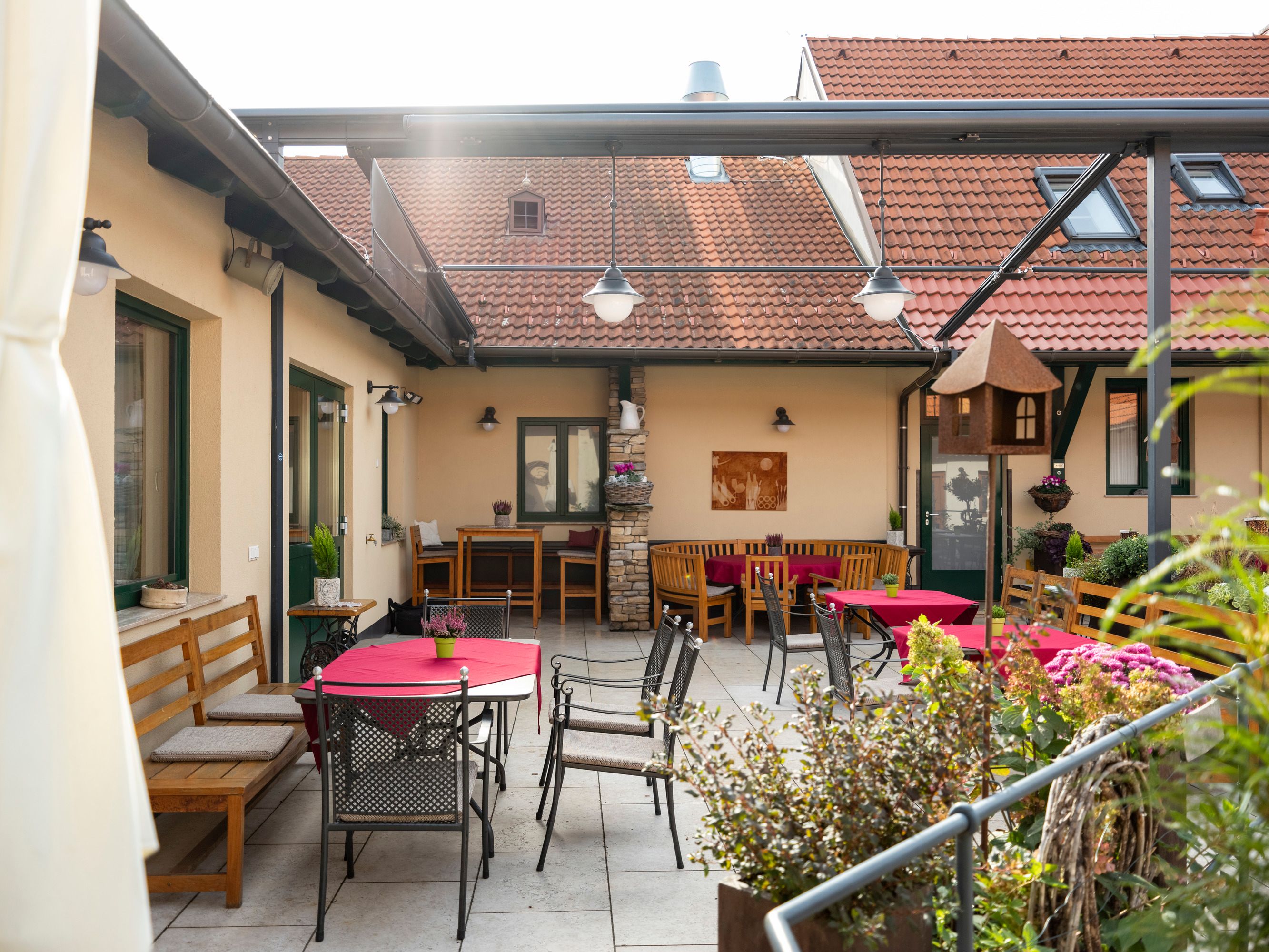 Cozy courtyard with seating and red tablecloths.