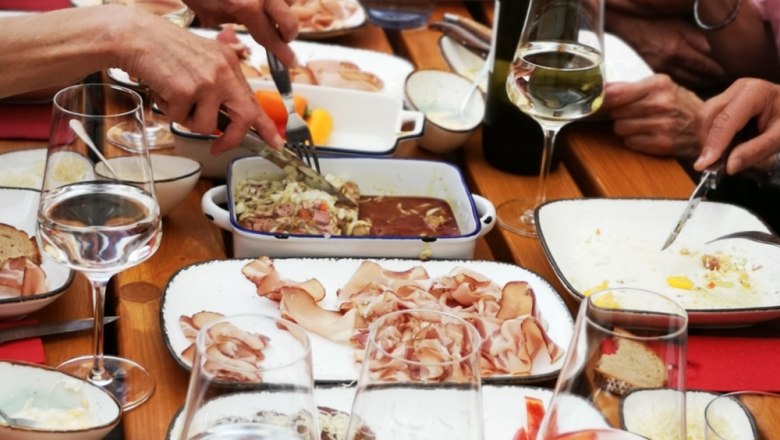 People eat together at a table with different food and drinks.