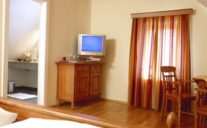 Cozy room with wooden furniture, TV and colorful curtains.