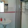 A bathroom with washbasin, mirror, shower and towel rack.