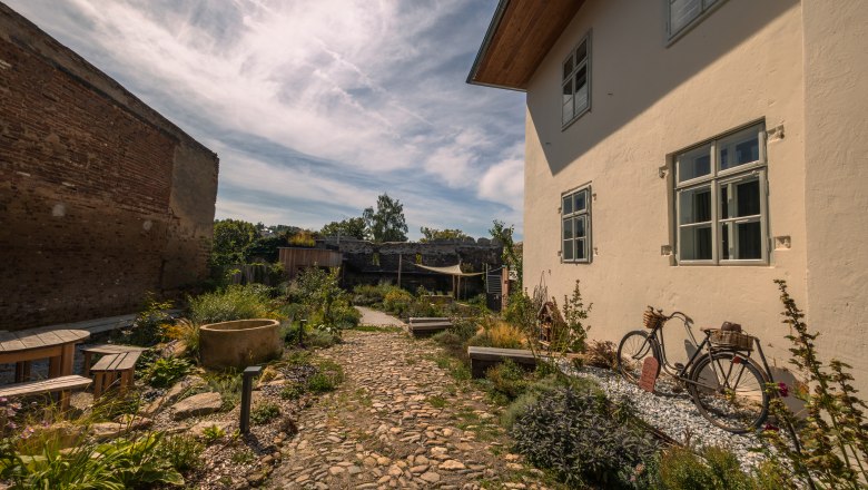 Garden with cobblestone path, bicycle and plants at SONNENTOR Stadt-Lofts.