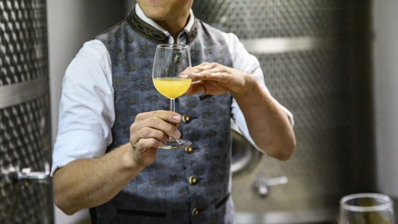 Person in traditional clothing holding a glass of Cider
