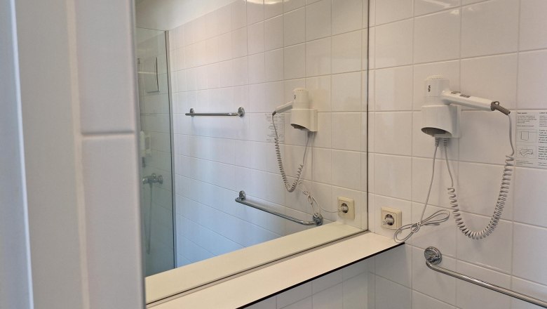 Modern bathroom with mirror, hairdryer and towel rail.