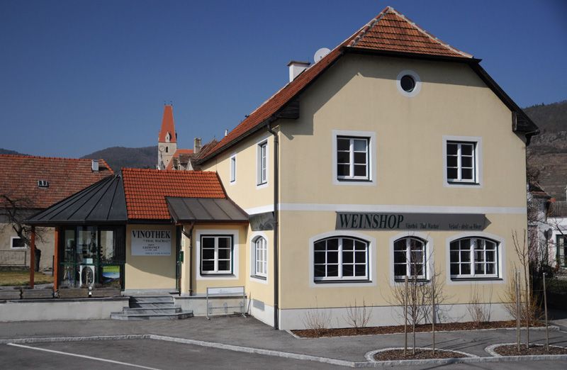 Yellow building with the inscription 'Weinshop' and 'Vinothek' in a rural setting.
