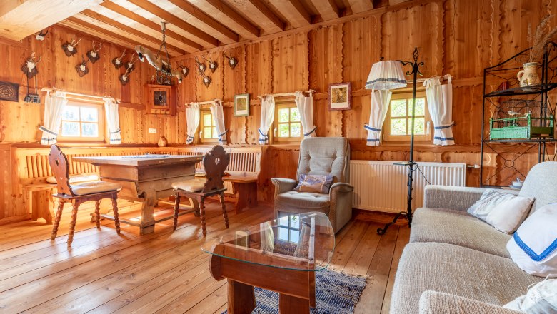 Rustic living and dining area with wooden furniture, wooden walls and hunting trophies on the wall.