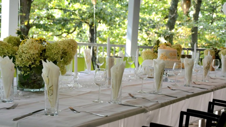 Solemnly laid table in white on a terrace with flowers and candles.