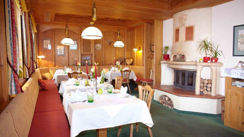 Cozy room with wooden walls, covered tables and fireplace.