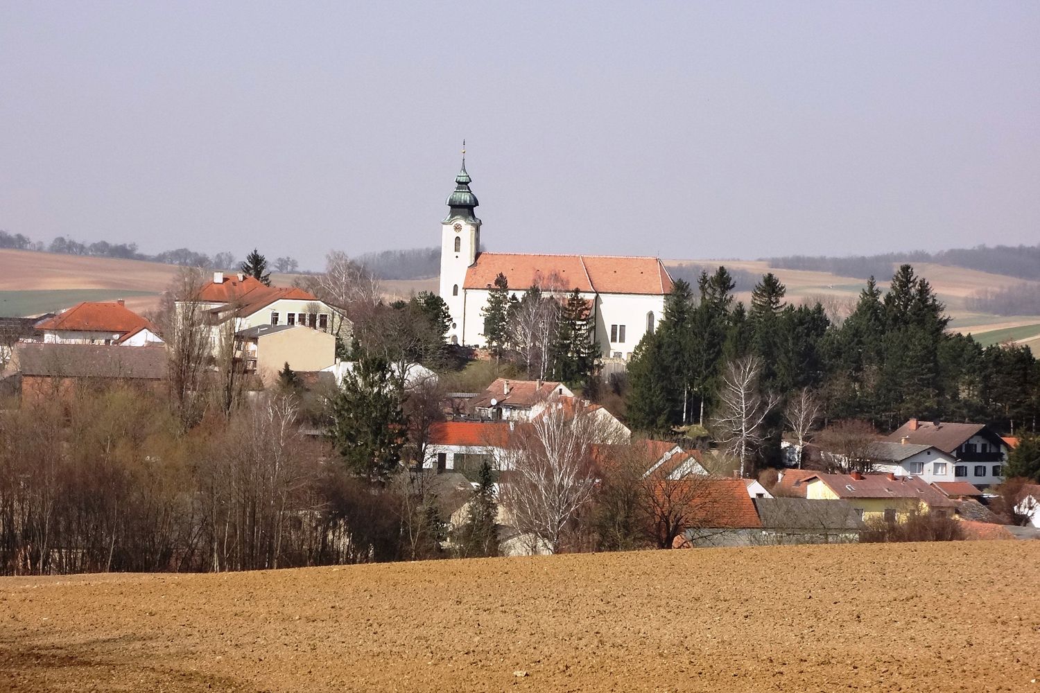 View of the village of Gnadendorf with church and surrounding houses in a rural landscape.
