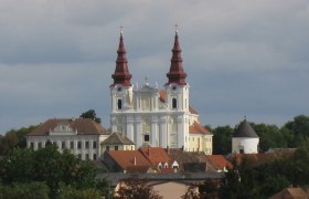 Baroque church with two towers and surrounding buildings.
