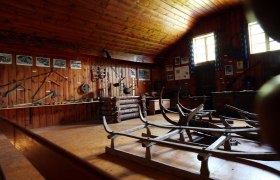 Interior view of a museum with wooden walls, old tools and sledges.