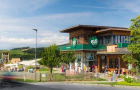 Building of the Eis-Greissler Welt with trees and visitors and view of the adventure park.
