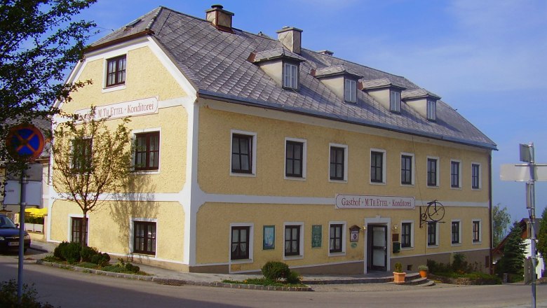 Yellow two-storey building with the inscription 'Gasthof M. Th. Ettel Konditorei'.