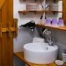 Bathroom with washbasin, mirror, hairdryer and wooden shelves.