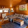 Cozy living room in a wooden hut with sofa, armchairs and decoration.