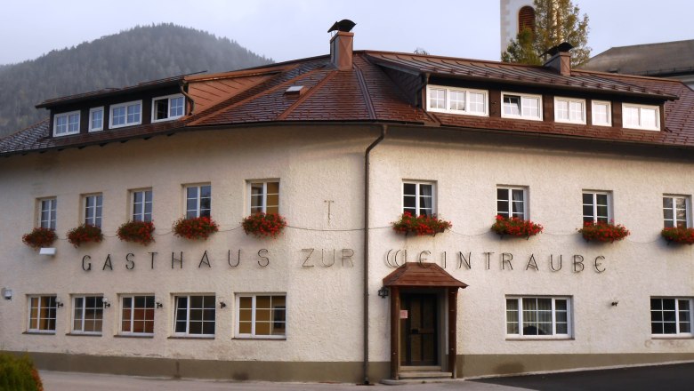 A traditional inn with flowers in the windows and a church tower in the background.