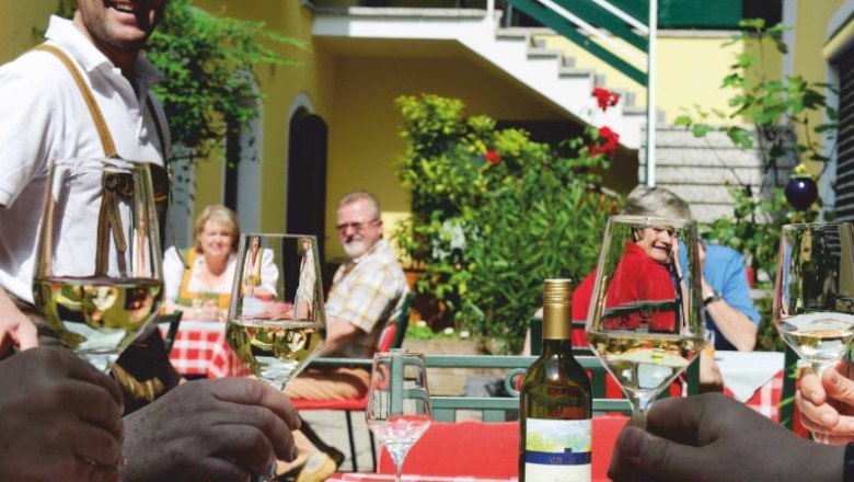 People clink glasses of wine in the sunny courtyard.