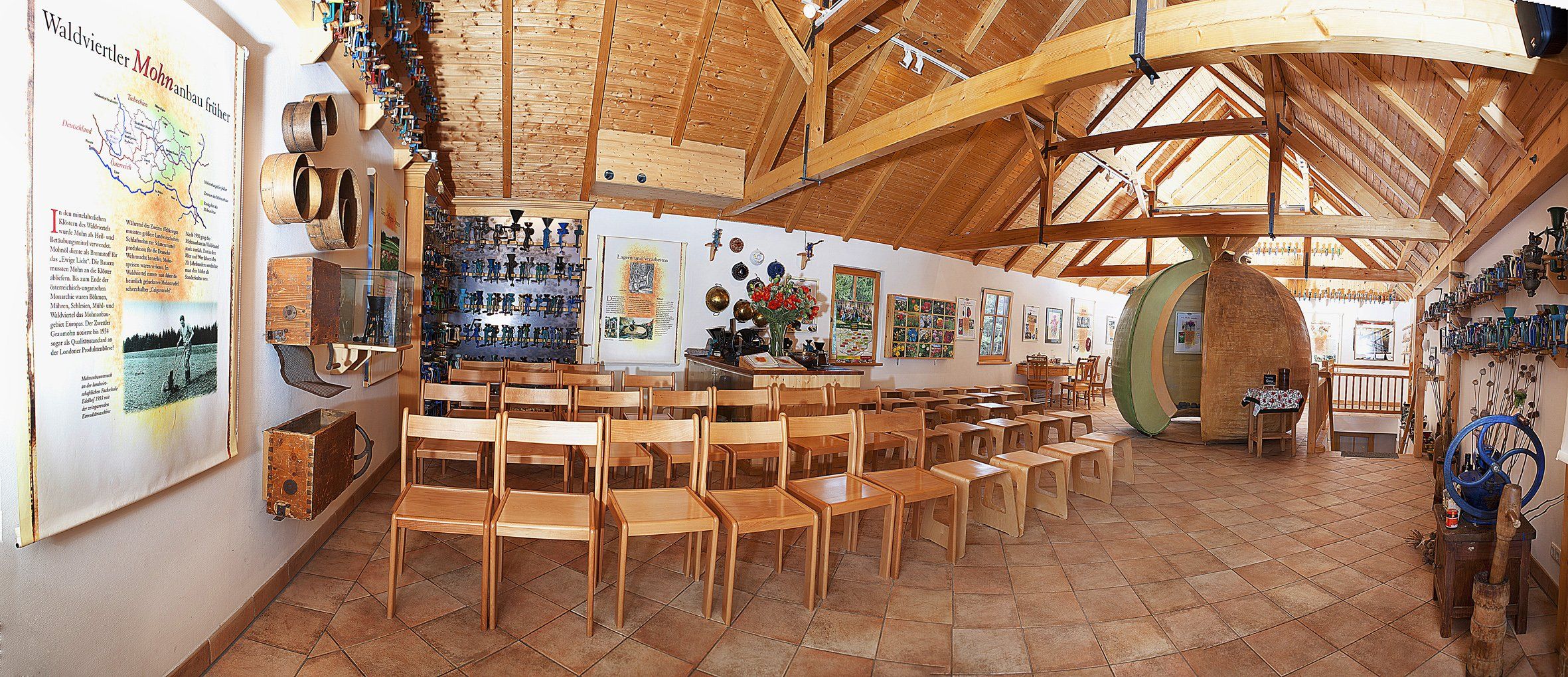 Interior view of a museum with wooden chairs, information boards and exhibits on the walls.