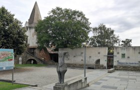 Town wall and museum in Horn with statue and information board in the foreground.