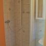 Small shower cubicle with tiles and shower head.