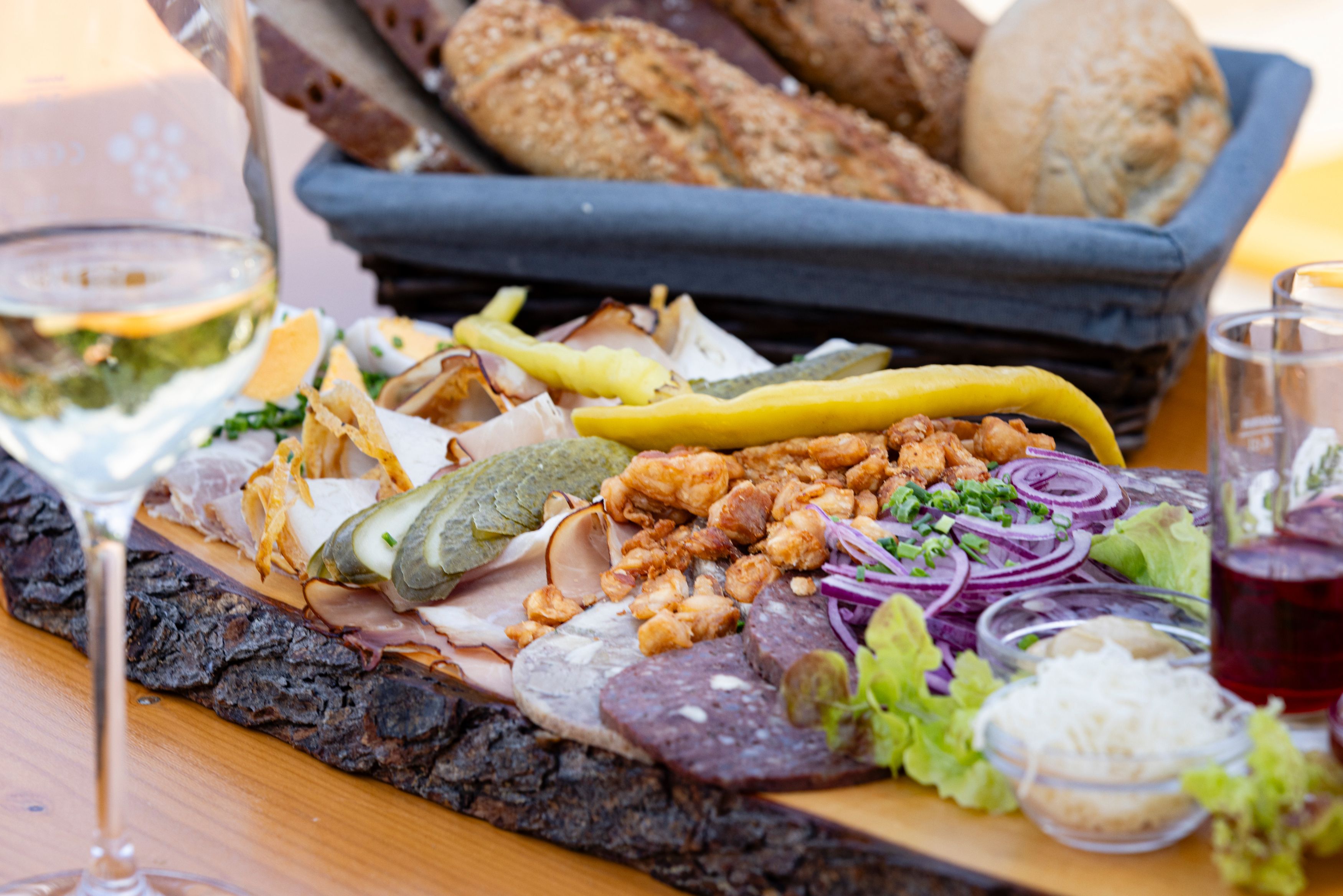 Heurigen platter with sausage, cheese, onions and bread on a wooden table.